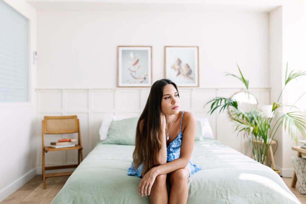 Sad young adult woman sitting on bed